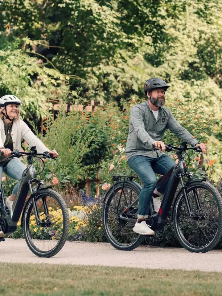 Deux cyclistes roulent sur des vélos électriques dans un parc